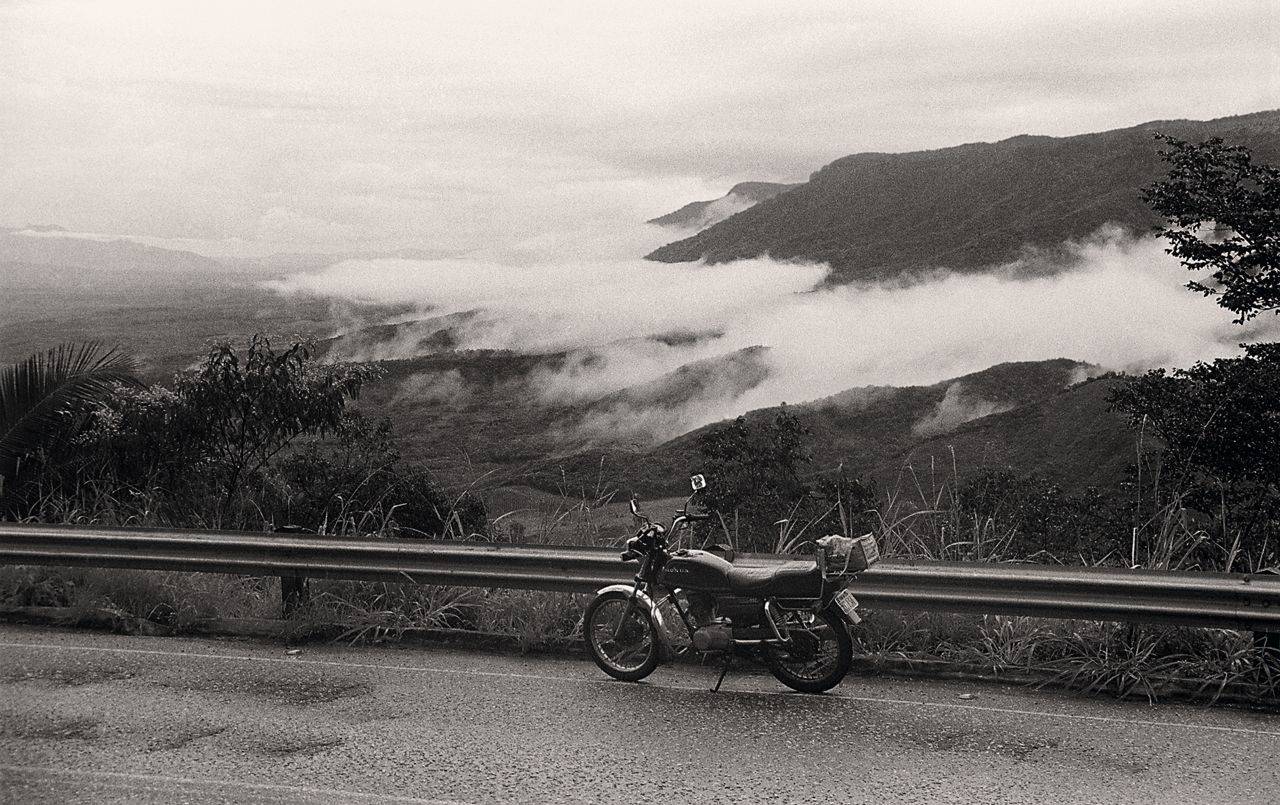 Moto Honda ML 125 em estrada com neblina e montanha ao fundo