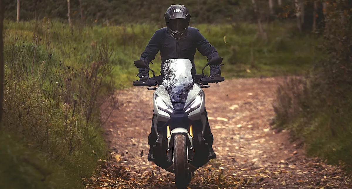 Piloto em sua Honda X-ADV em estrada no meio da natureza