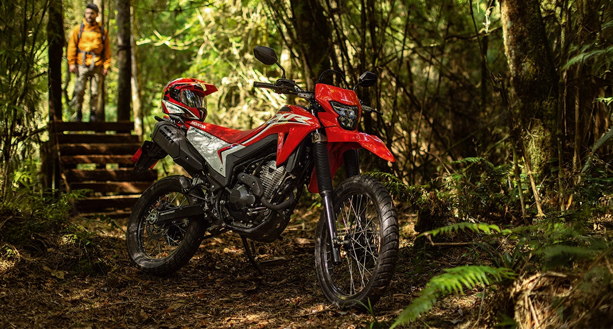 Moto Honda XR 300L Tornado vermelha com capacete no banco