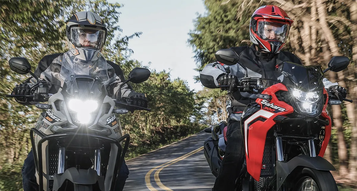 Dois pilotos em suas motocicletas XRE 300 e Sahara na estrada e com os faróis ligados