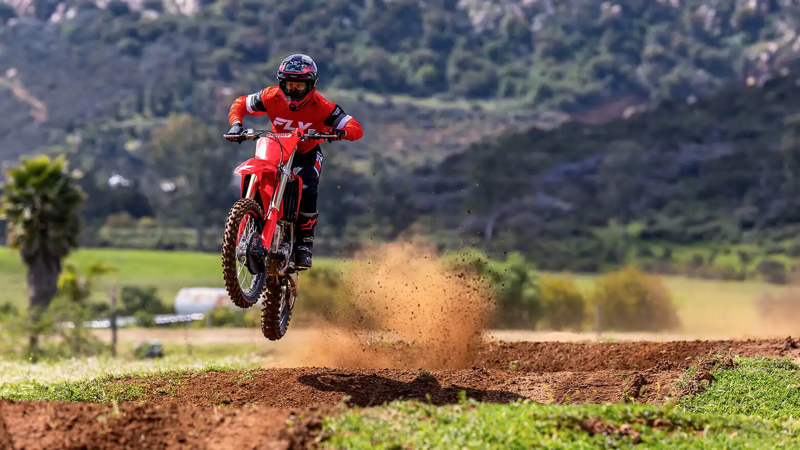 Piloto saltando em estrada de terra com sua Moto Honda CRF 450 
