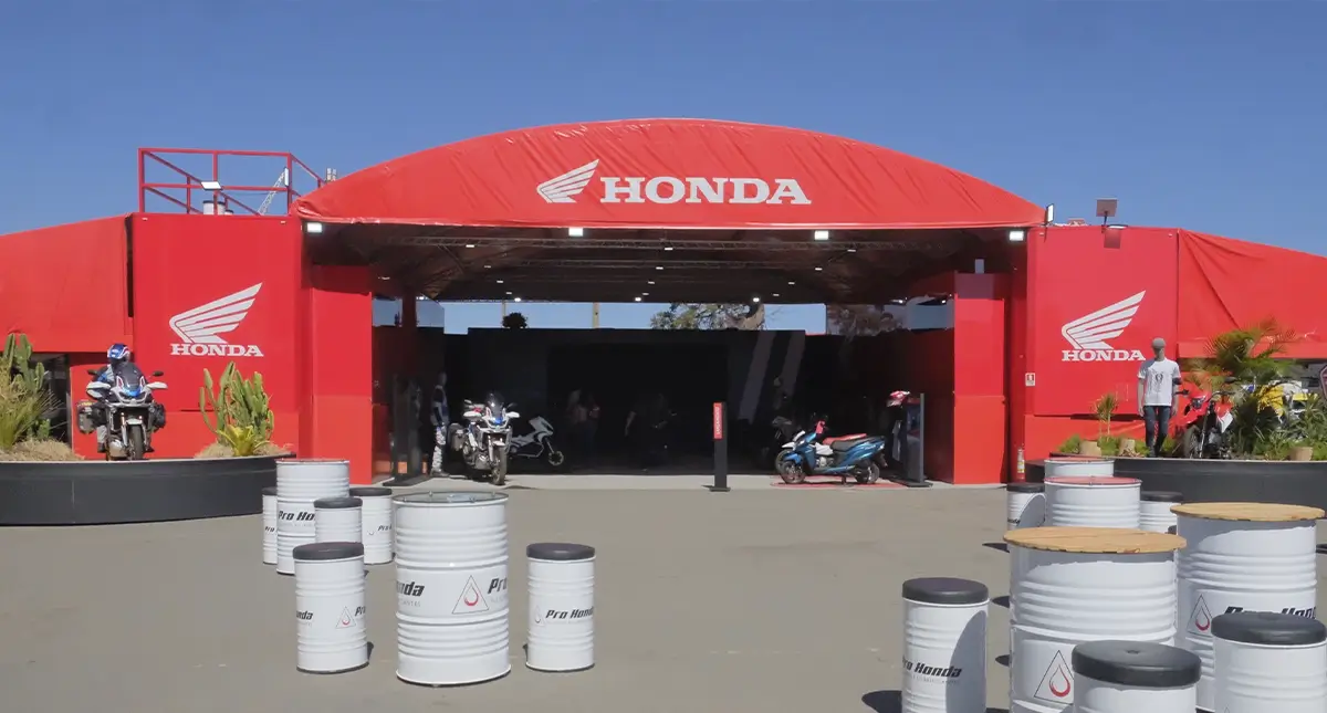 Entrada principal do estande da Honda no evento, com tambores metálicos decorativos e logotipo centralizado