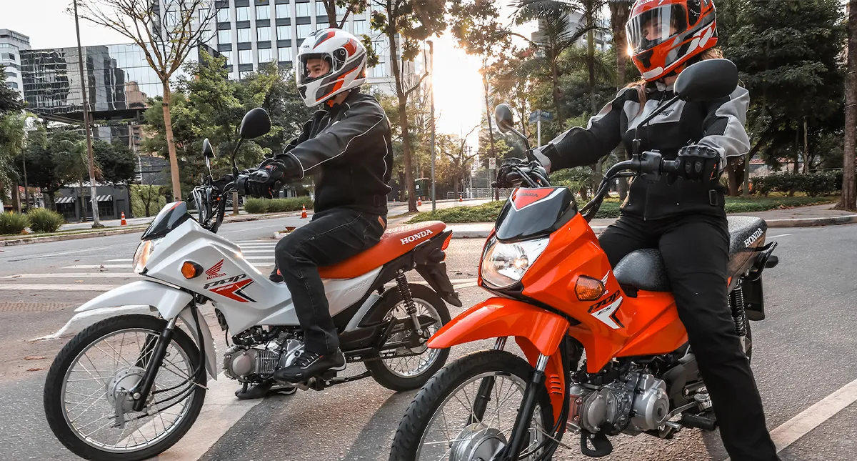 Pilotos um homem e uma mulher em suas motocicletas Honda Pop 110i ES