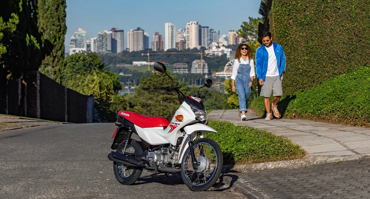 Casal ao fundo indo ao encontro da sua Honda POP 110i ES