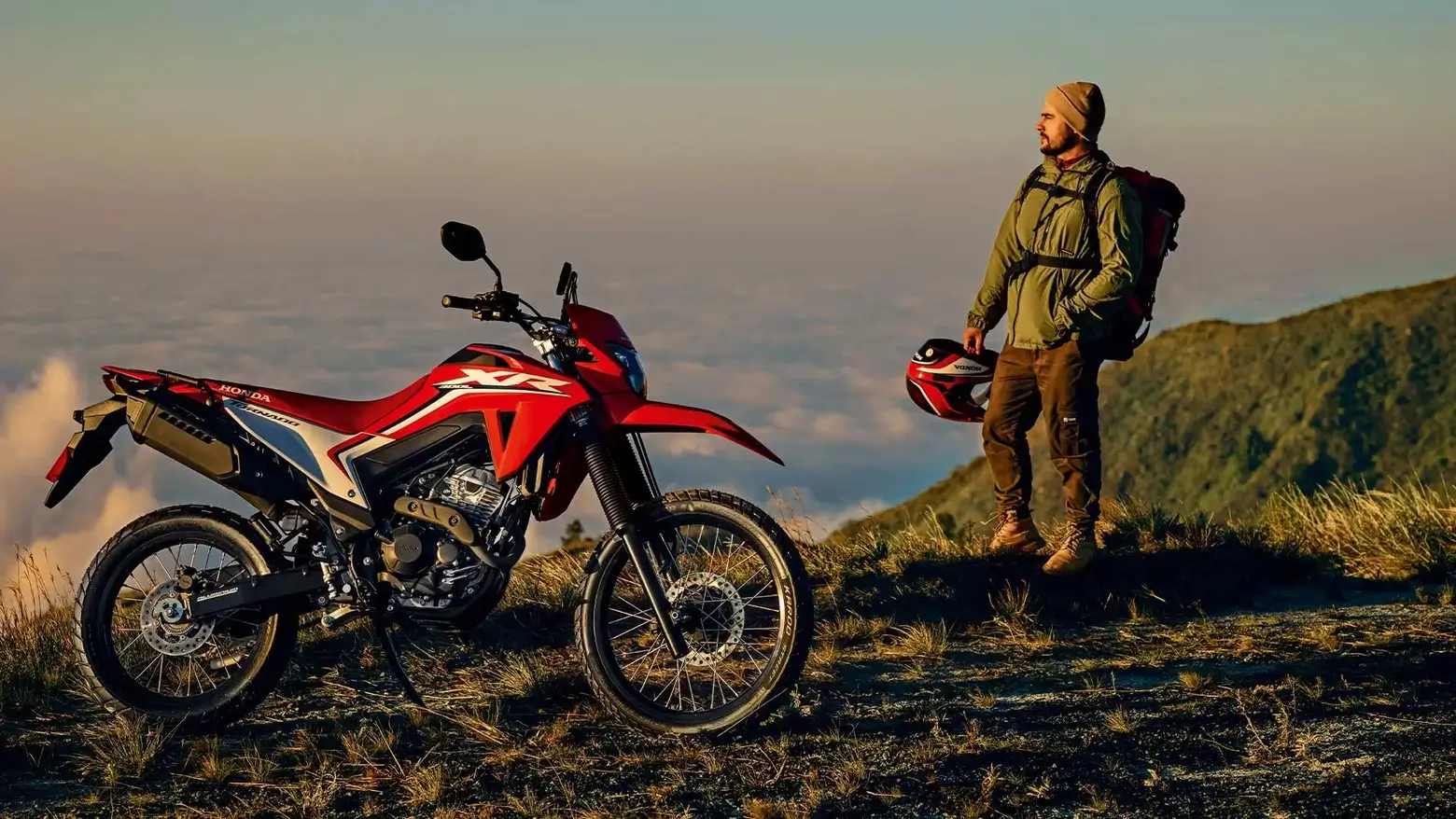 Homem ao lado da Moto Honda XR 300L Tornado em cima de montanha