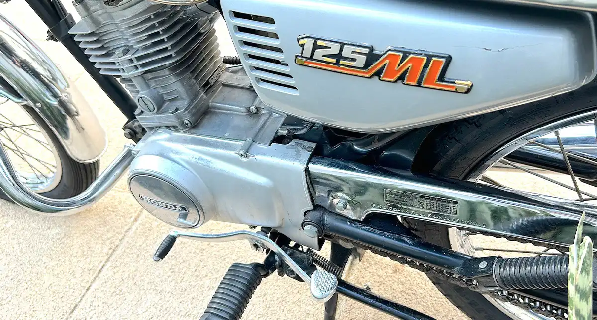 Detalhe do motor da Honda 125 ML, mostrando componentes e o logo