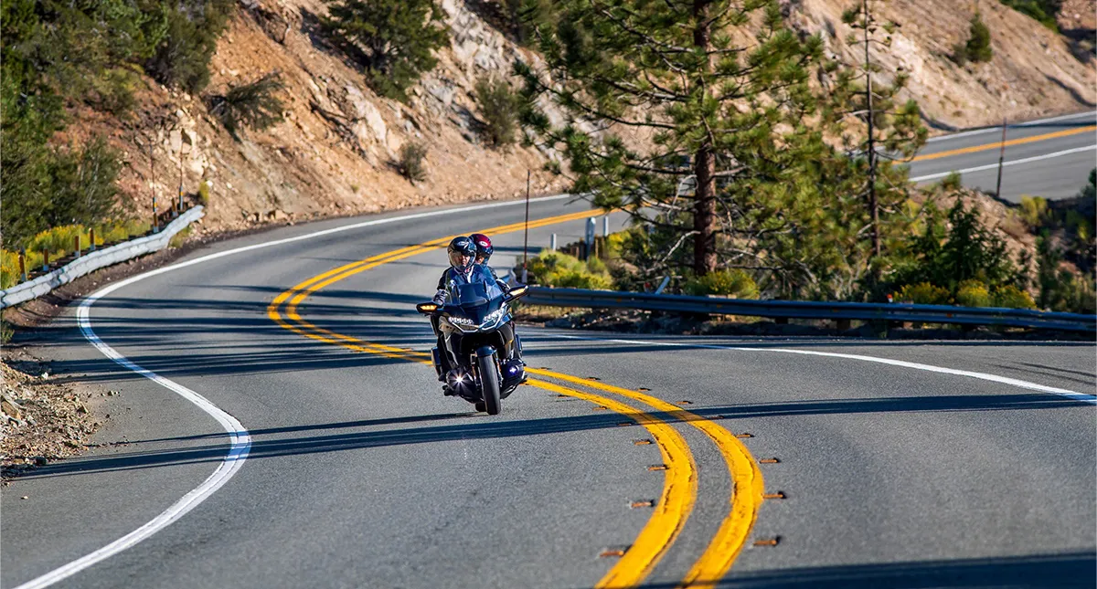 Piloto e garupa na estrada curva com Gold Wing 