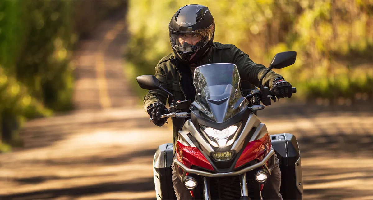 Piloto com sua Moto Honda NC 750X na estrada, detalhe frontal