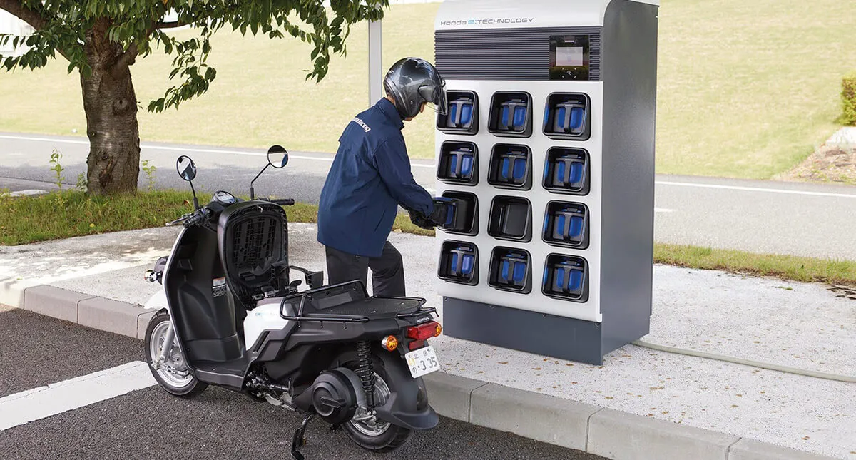 Homem pegando nova bateria na estação de troca de baterias da Honda