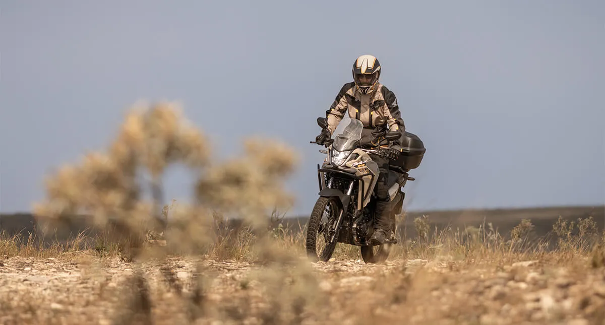 Piloto com moto Honda Sahara 300 Adventure em estrada de pedra