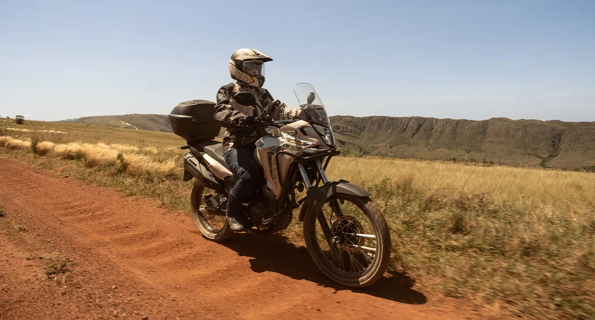 Piloto em estrada de terra com moto Honda Sahara 300 Prateada