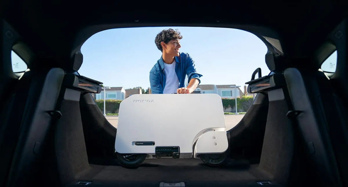 Homem colocando a Honda Motocompacto em um porta malas Honda