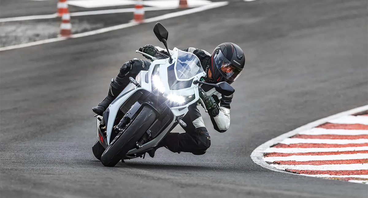 Piloto fazendo curva em sua motocicleta com faróis ligados