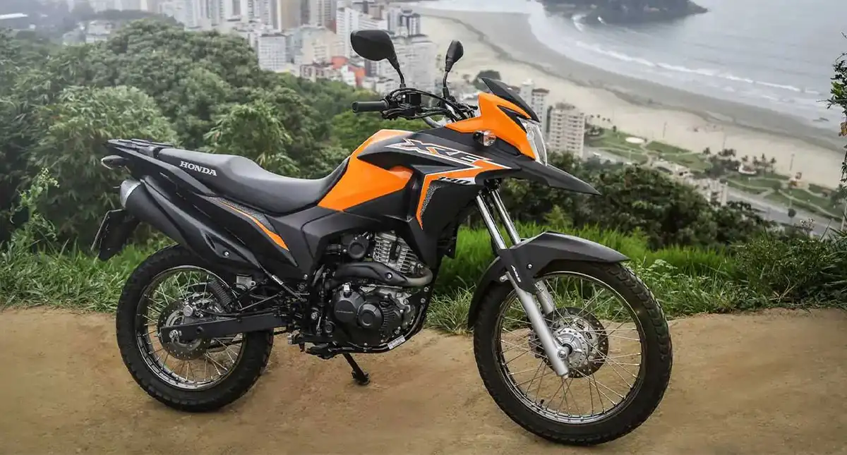 Honda XRE 190 laranja com praia ao fundo
