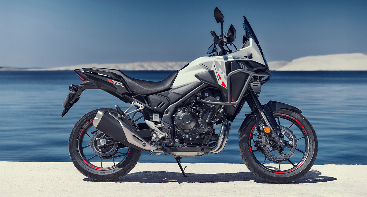 Honda NX500 2024 branca estacionada à beira-mar