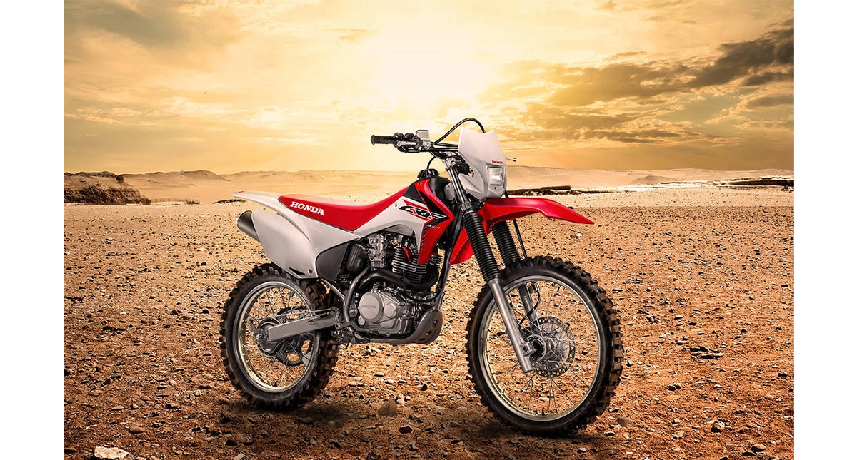 Moto Honda CRF230F vermelha em paisagem desértica ao pôr do sol
