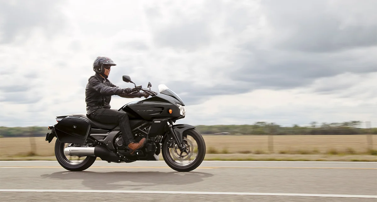 Homem pilotando uma Honda na estrada 