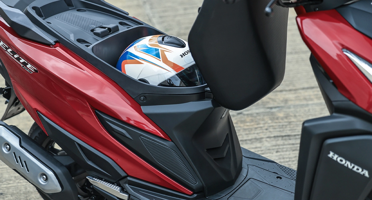 Compartimento sob o banco de uma scooter vermelha aberto