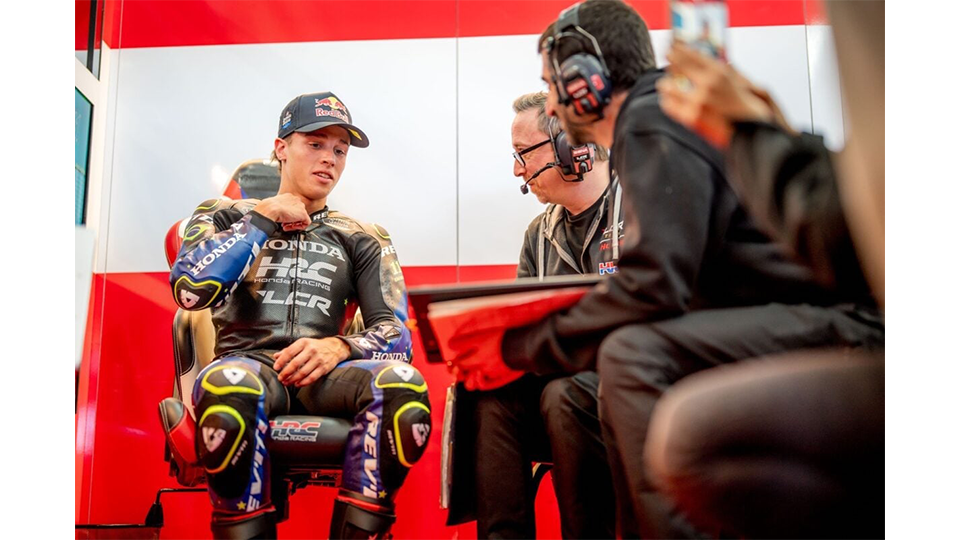 Piloto Honda sentado no box com seus técnicos